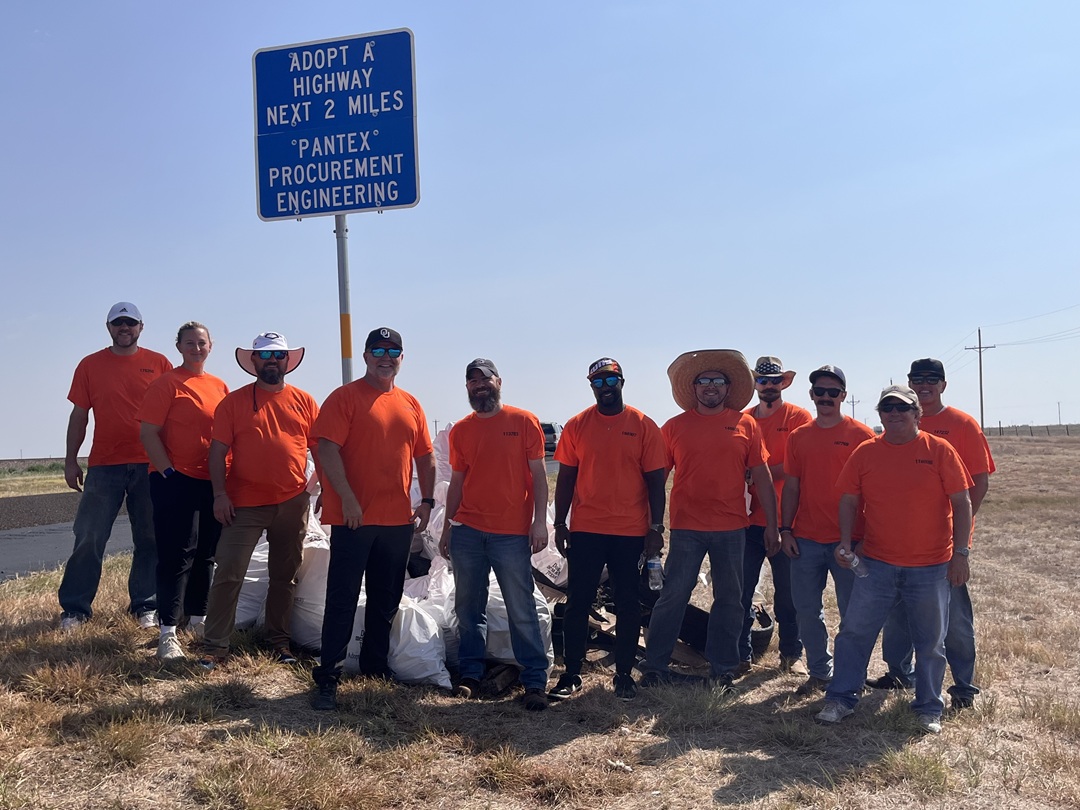Members of the Procurement Engineering Group (left to right) James Hyde, Carissa Goulbourne, Thomas Hunt, K.J. Trosper, Wes Townsend, Chris Jamison, Antonio Jimenez, Andrew Zielinski, Sam Nazworth, David Kraman, and Kevin Henry recently volunteered to clean up a two-mile stretch of highway, where they collected nearly 40 large bags of trash. Also volunteering but not pictured were Alex Tow, Cynthia Tivis, and Johan Gonzales. A group of men and women wearing bright orange T-shirts stand in front of a large pile of white trash bags under a road sign reading, “Adopt-A-Highway next two miles. Pantex Procurement Engineering.”